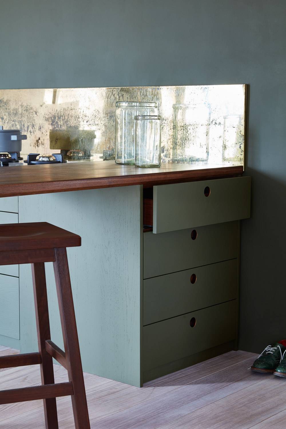 A detailed view of the Ladbroke kitchen's sleek cabinets, showcasing the subtle grain of the solid walnut wood and the smooth finish of the Samphire Green paint. The generous storage space, including hidden features like walnut cutlery inserts and peg boards, is evident in this image.