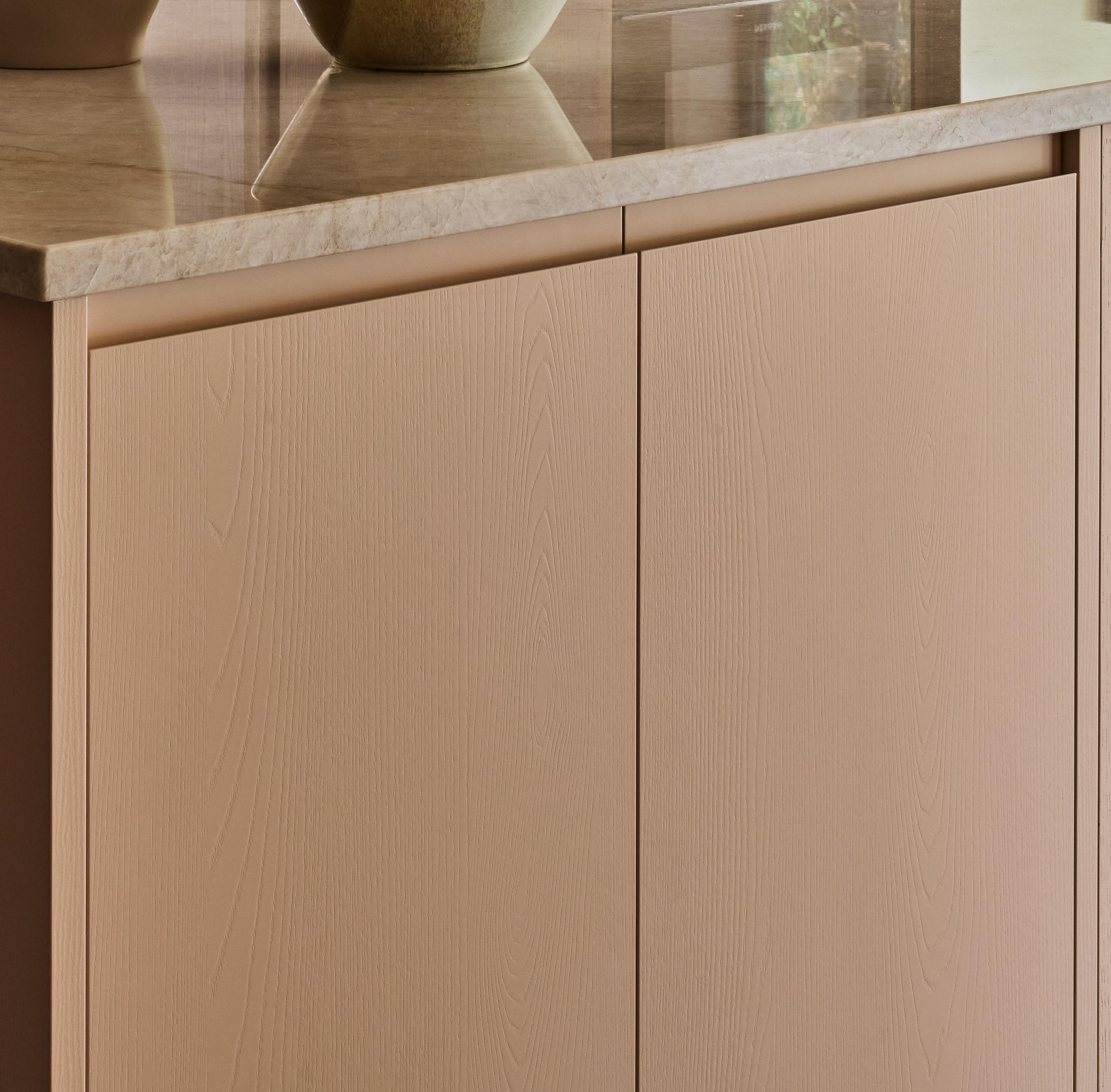 Light blue kitchen cabinet with a wood grain pattern. It has a simple design with a round, dark metal knob. Golden hinges attach the cabinet door to the frame.