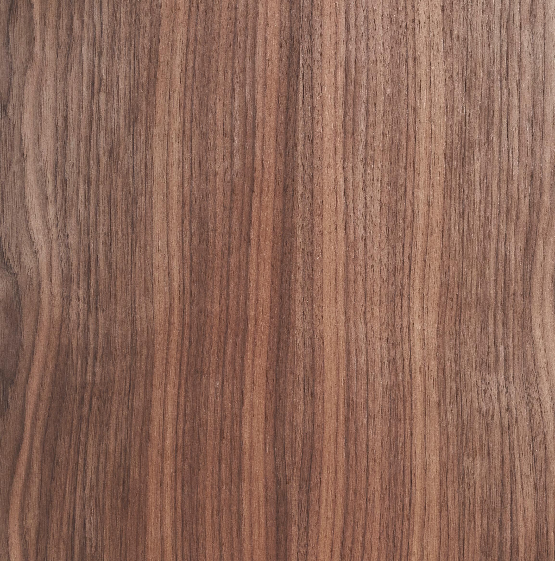 Wooden surface with a smooth, natural grain pattern. The woods color varies from light to dark brown, with vertical, wavy lines creating an organic texture. The surface appears polished and consistent across the image