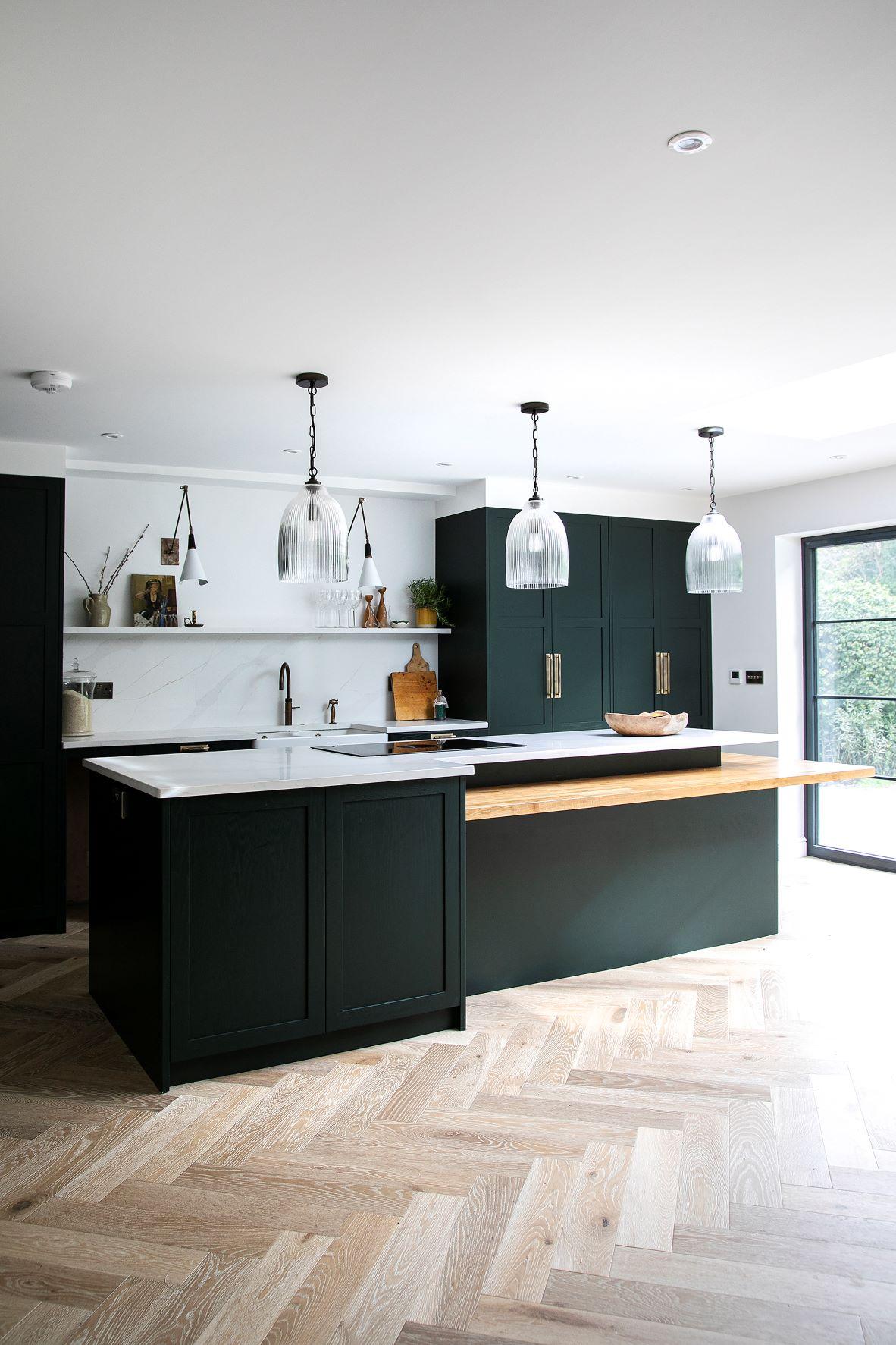 A captivating view of the Westward Ho kitchen, featuring Sandringham Pine cabinetry, a modern white backdrop, and a sleek oak breakfast bar.