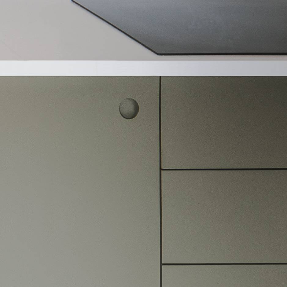 Minimalist photo showing part of a grey and white cabinet with flat surfaces, sharp lines, and a single round indented button detail near the top left corner.