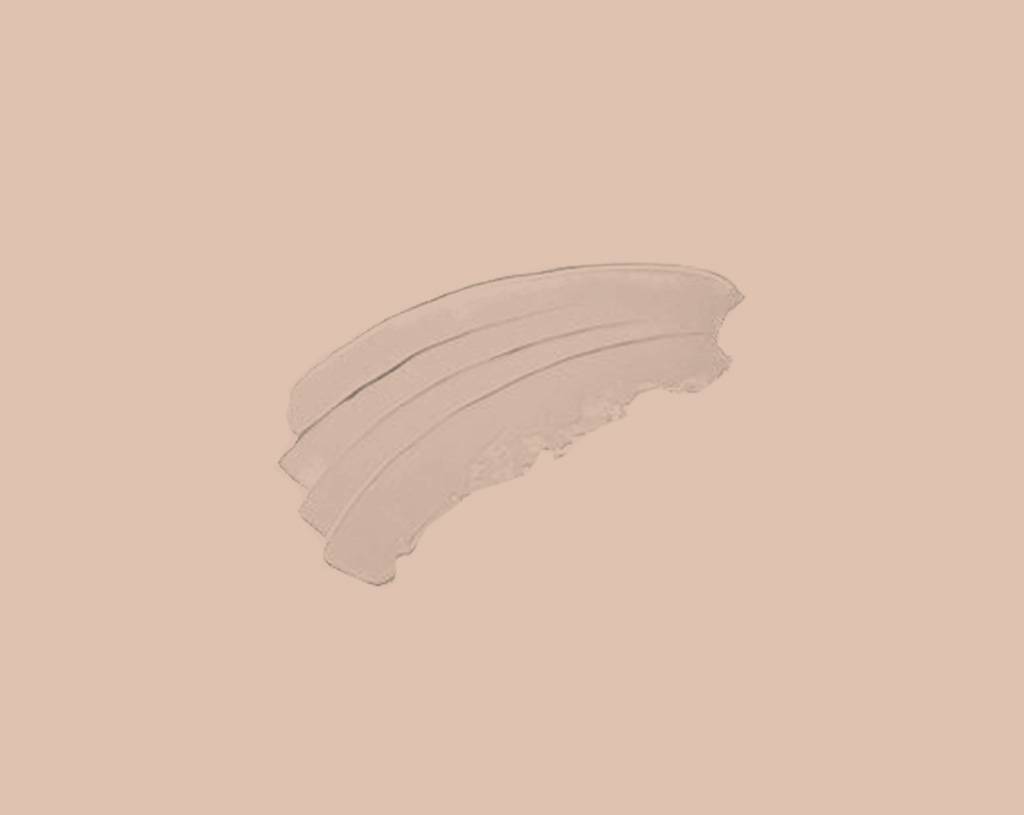 Three smooth, curved swipes of a creamy, beige cosmetic product are spread on a solid light peach background.