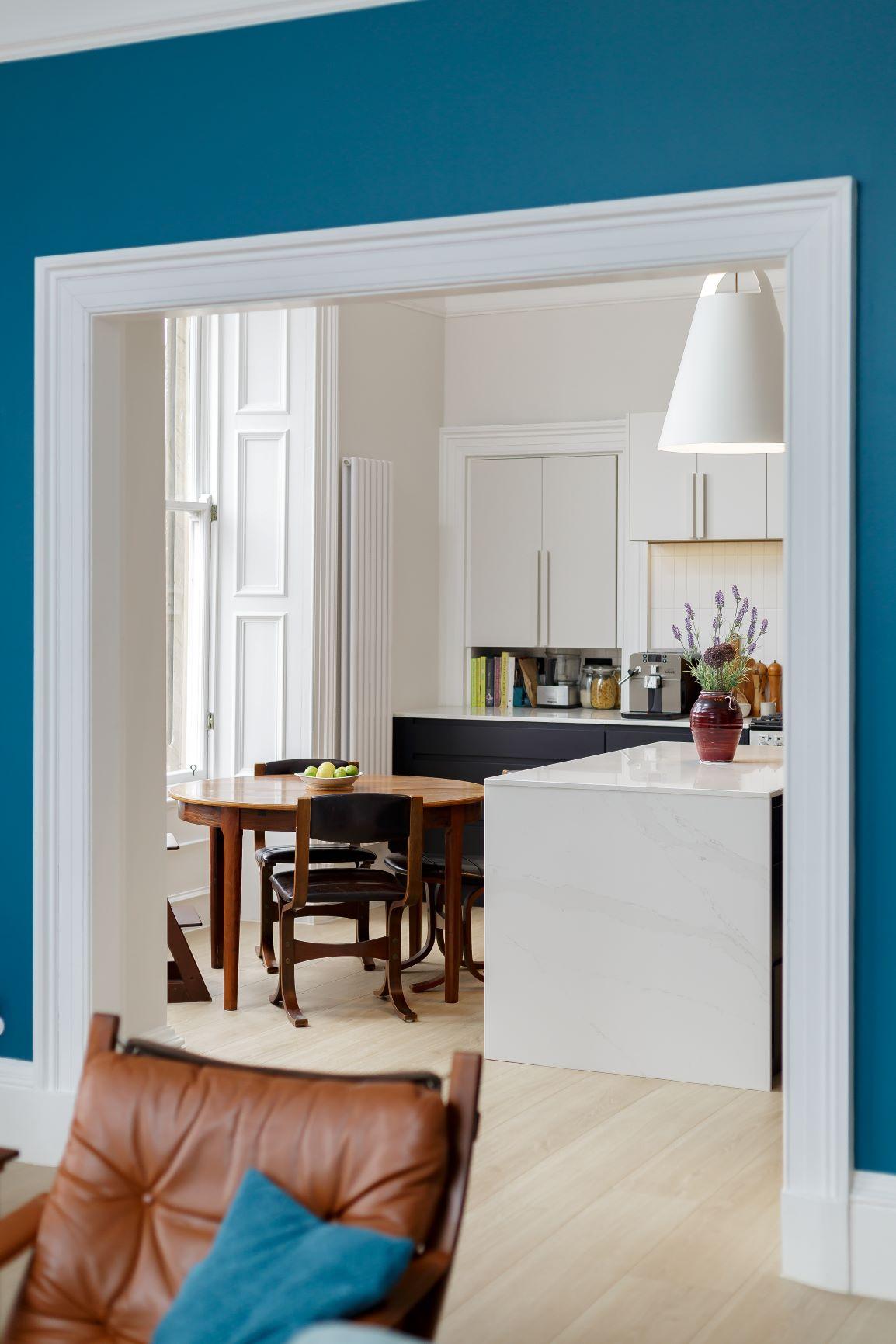 Expansive view of the Howard Place kitchen, highlighting the spacious layout and harmonious blend of black and white cabinetry. The island, with its waterfall edge and ample countertop space, serves as the heart of the culinary haven.