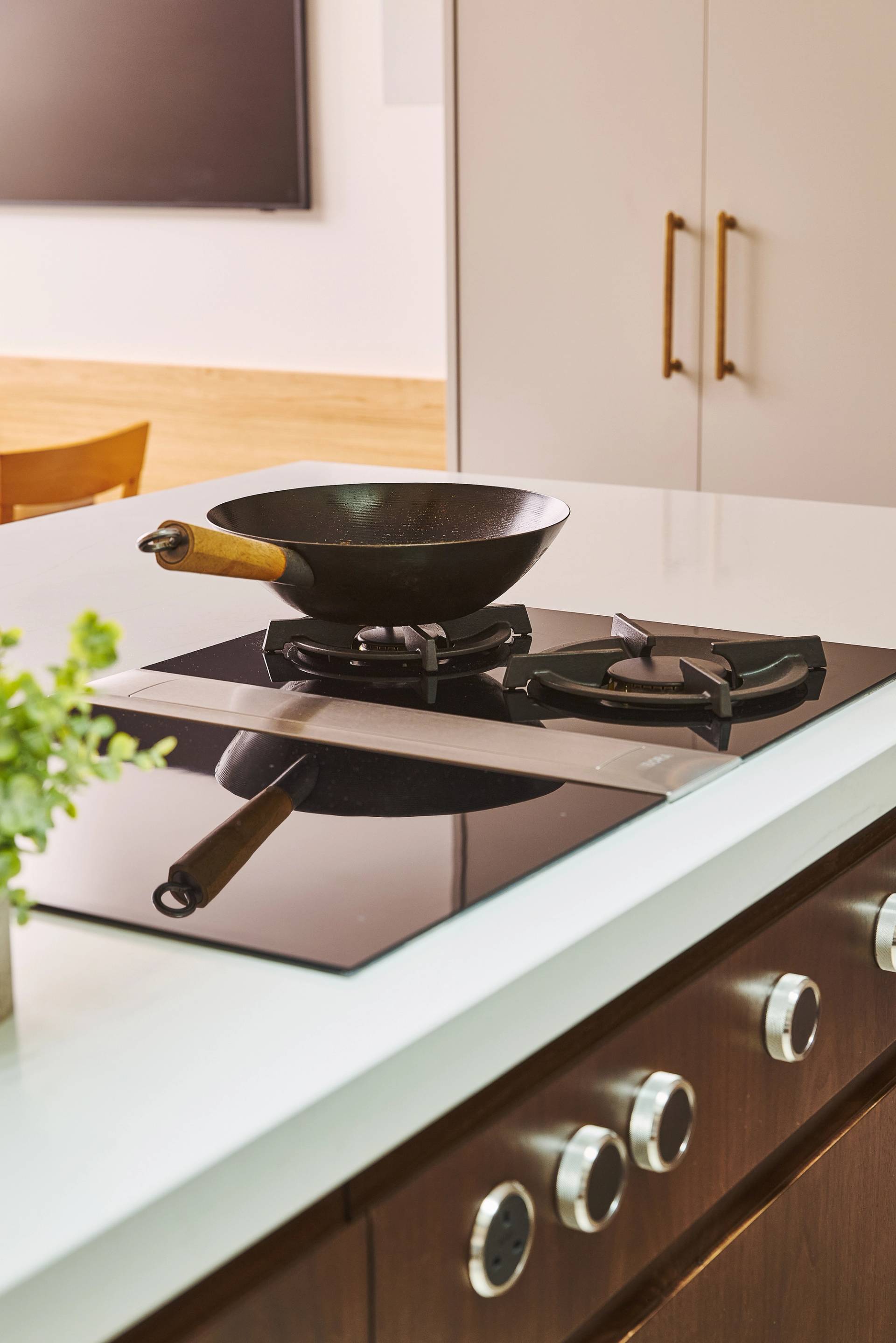 Close-up of a modern kitchen counter with a white marble surface and wooden front, featuring two black metal bar stools with slatted seats and backs.
