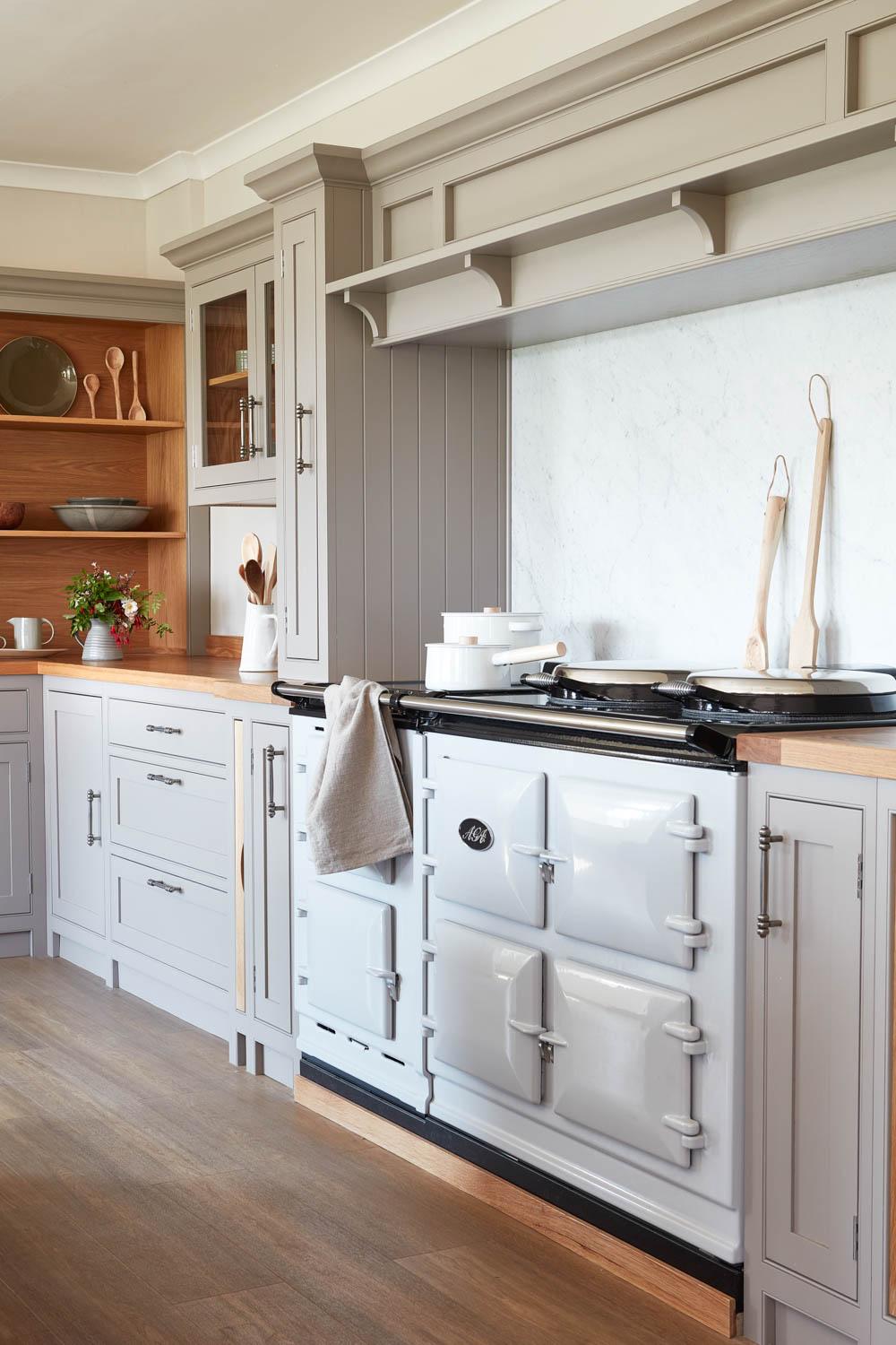 Glazed units and open shelves add depth and light, showcasing beautiful tableware and enhancing the spacious feel.