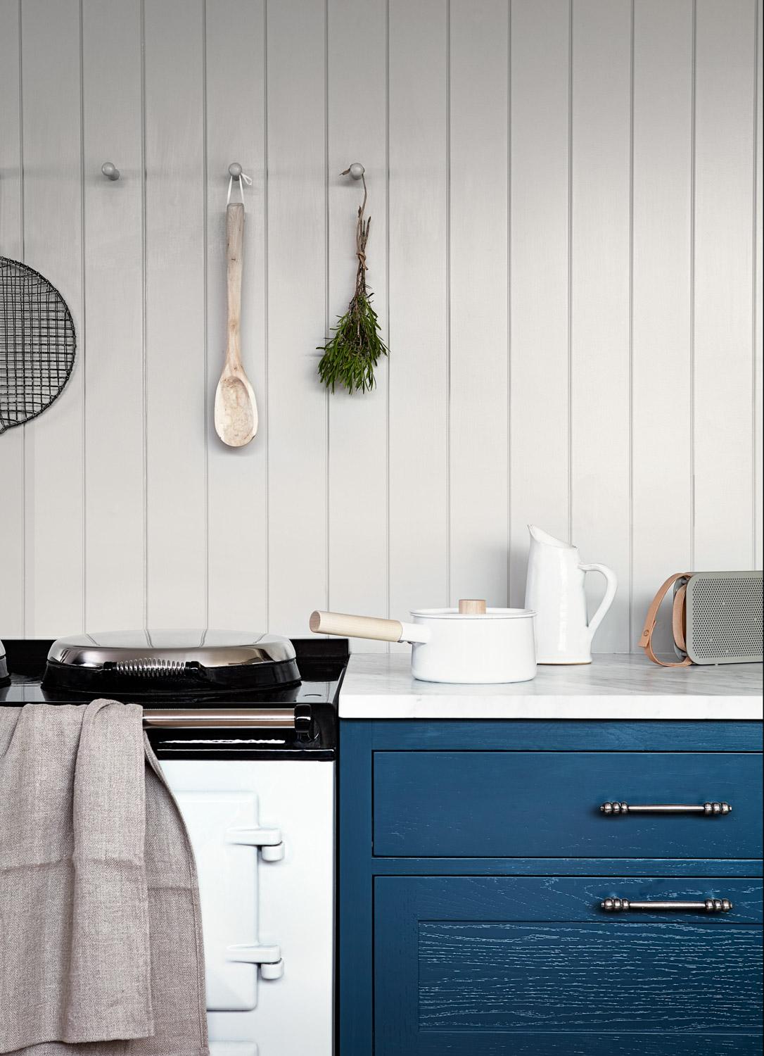 The warm blue shaker cabinets create a cozy and inviting ambiance, while the sleek white quartz countertop adds a touch of sophistication. The oven and the V-groove splashback complement the cabinetry perfectly, creating a cohesive and stylish design