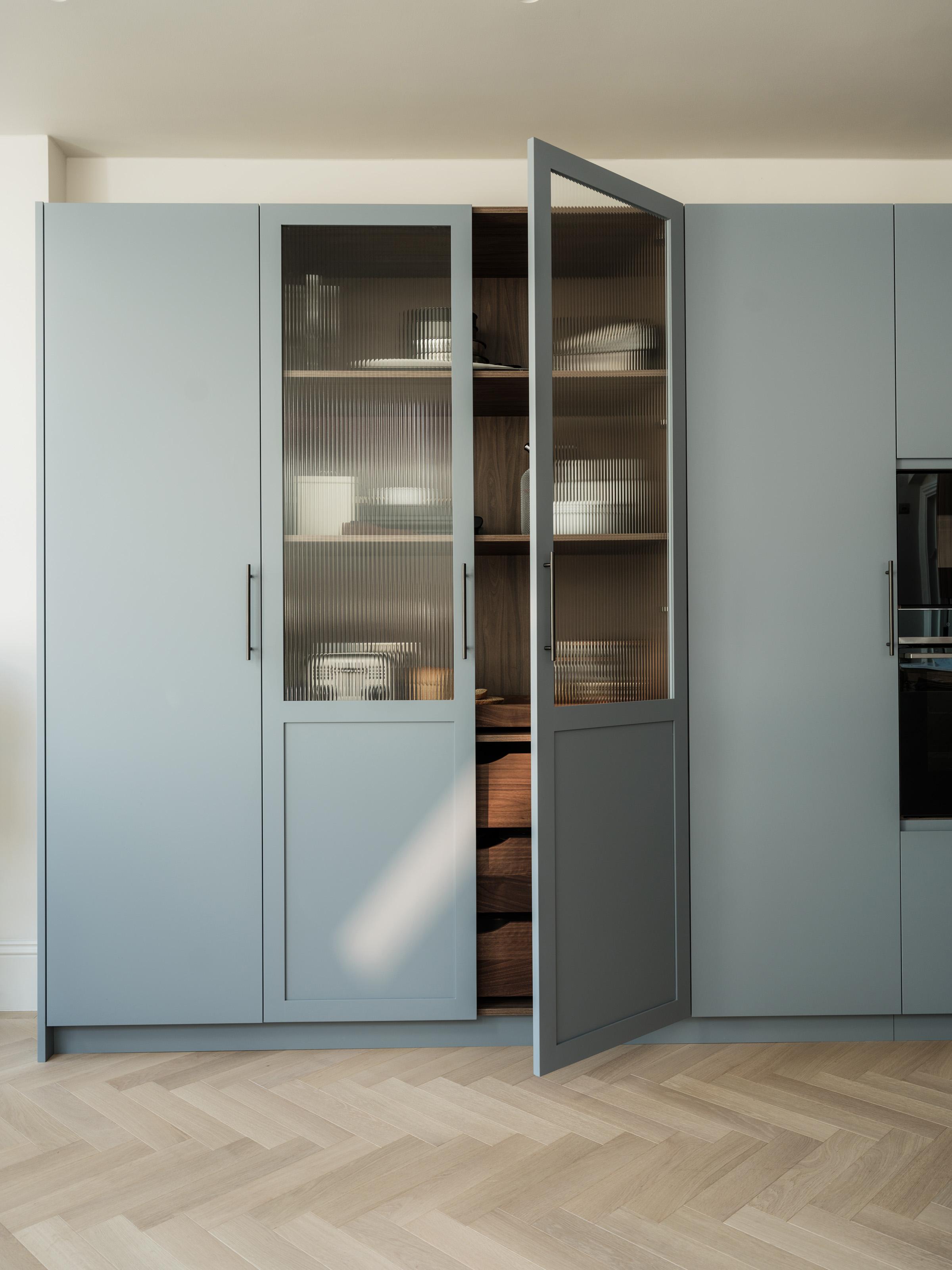 Glazed larder in the Maida Vale kitchen by Naked Kitchens, with First Flight blue and walnut cabinetry