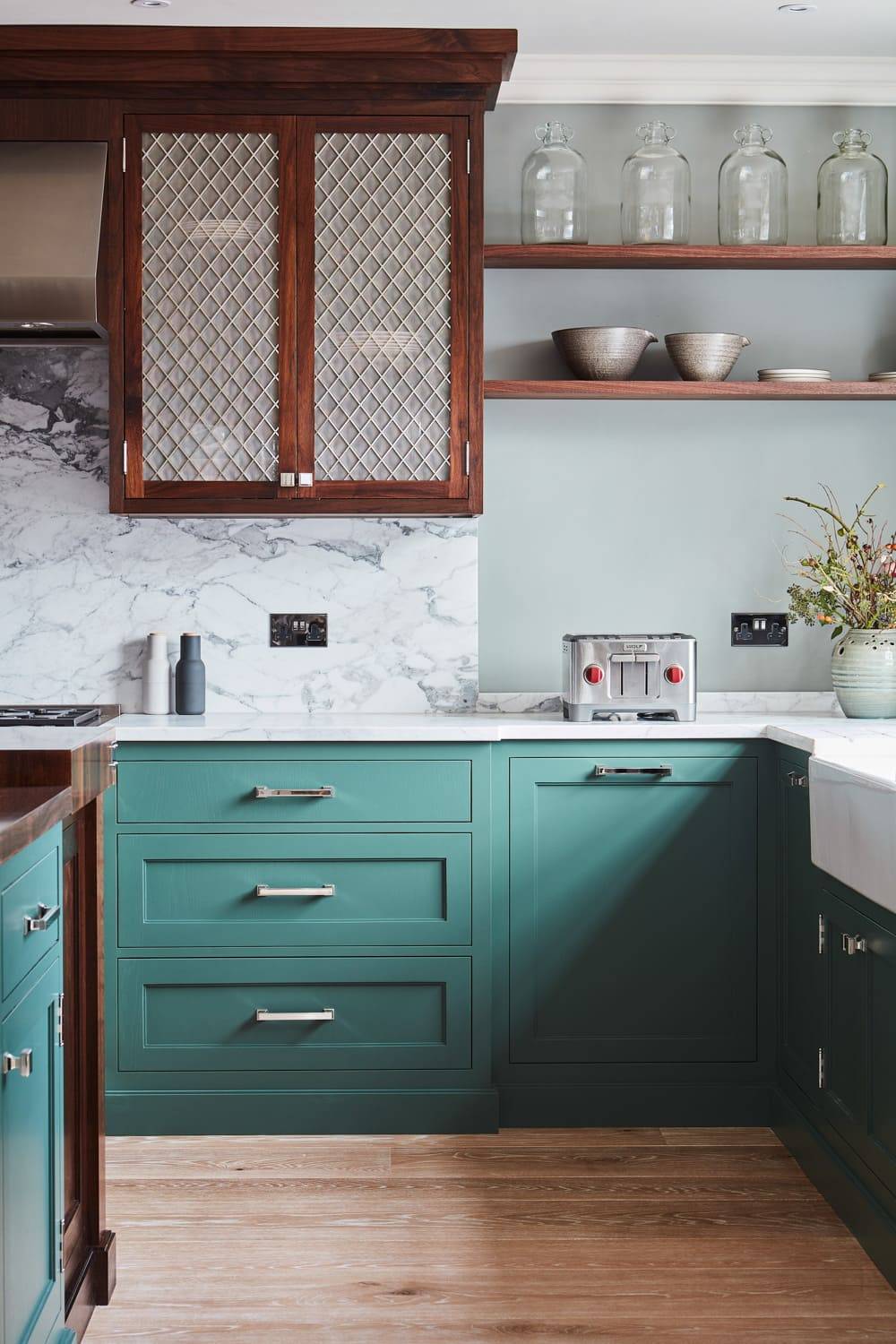 The Georgian Hall kitchen exudes timeless elegance, blending green Shaker cabinetry with white marble countertops, walnut worktops, mesh centrepieces, and a central island. The kitchen's simplicity and functionality make it a perfect centrepiece for any home.