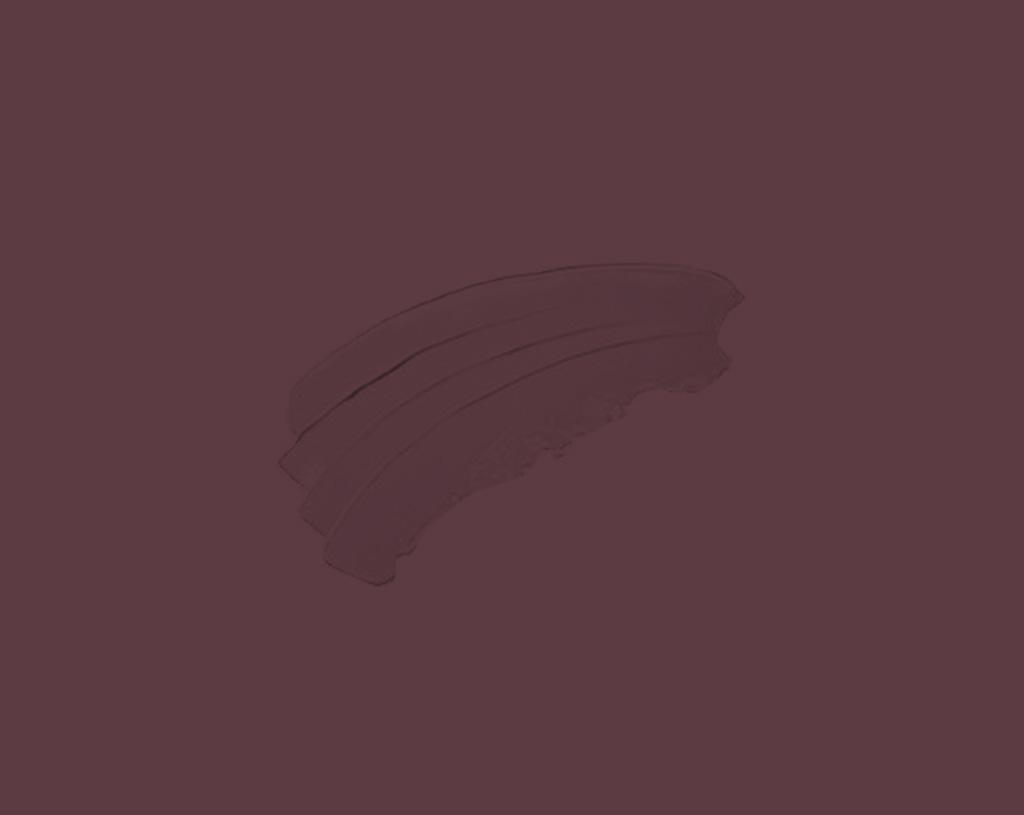 A swipe of dark maroon or plum-colored makeup product, such as lipstick or eyeshadow, is smeared on a solid matching maroon background.