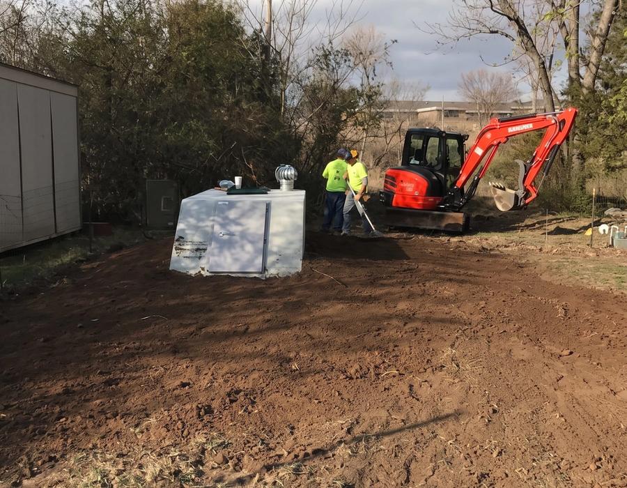 An excavator setting a storm shelter in a back yard
