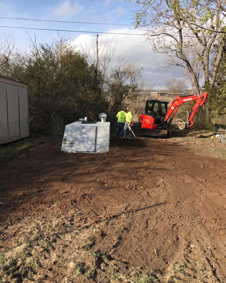 An excavator setting a storm shelter in a back yard