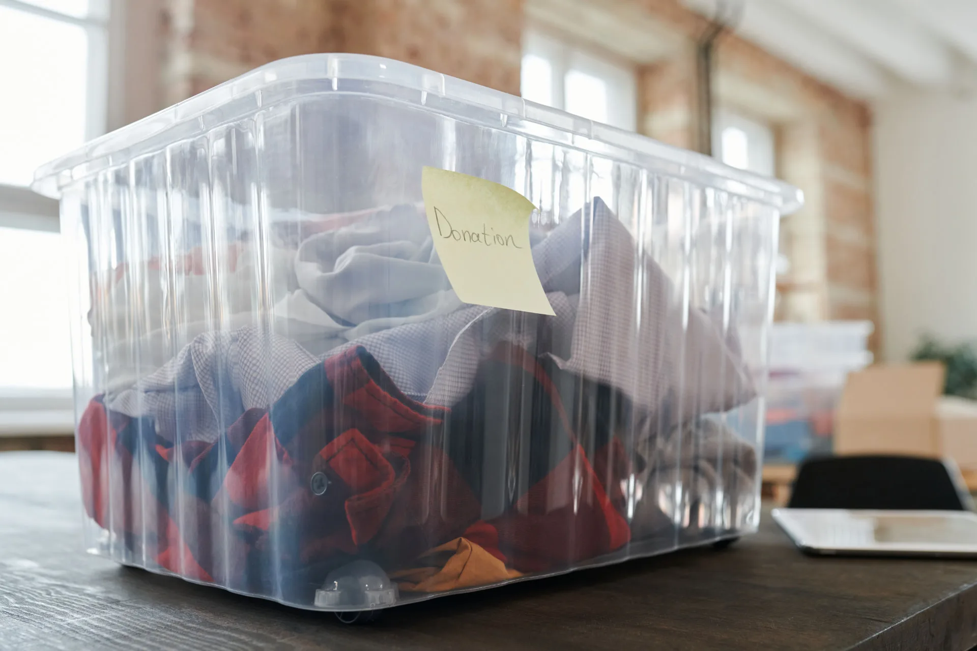 Transparante opbergbox met gesorteerde kleding en een label 'donation'