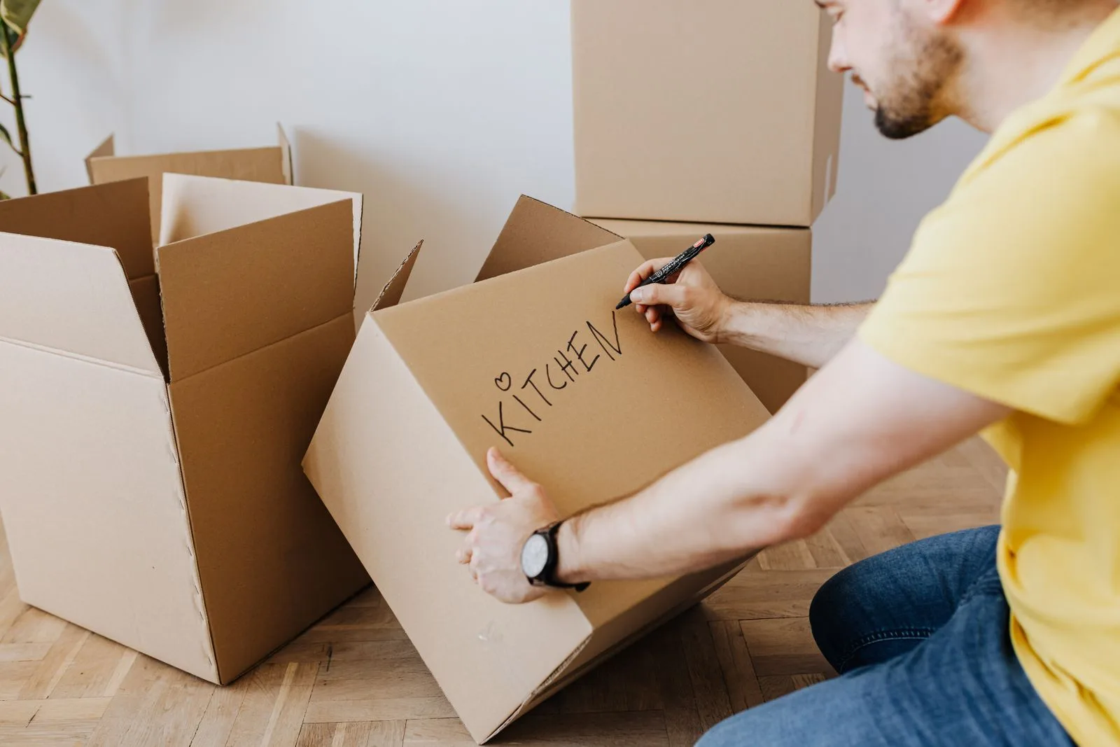 Een man schrijft een label op een verhuisdoos