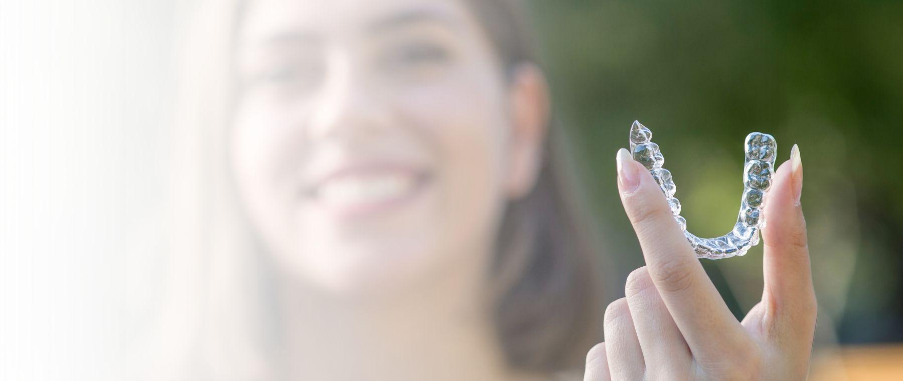 Clear aligners in Karachi held up by a patient at DentoCorrect