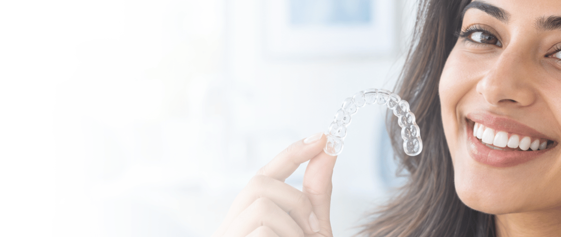 Clear aligners in Multan: patient holding a clear aligner tray beside her smile