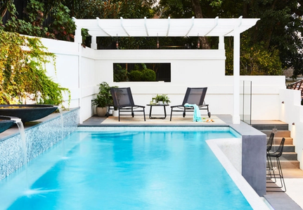 Pool with water feature, sitting area and pergola.