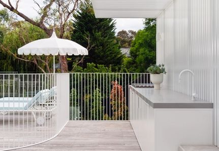 decking with outdoor kitchen and white steel pool fencing in the background