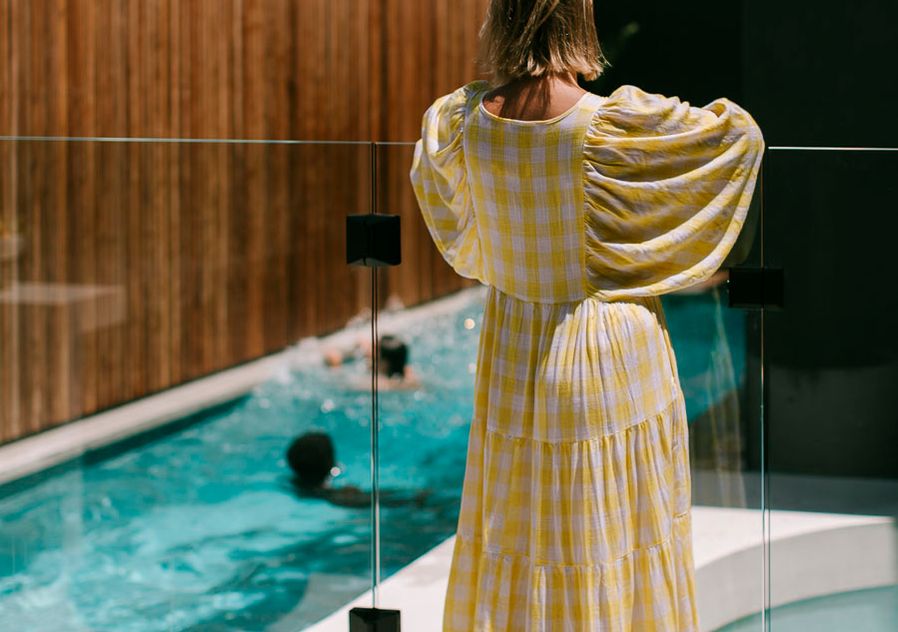 Sarita wearing a yellow dress overlooking boys playing in the pool