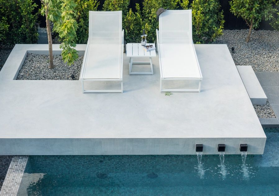 sun lounges next to pool with water feature