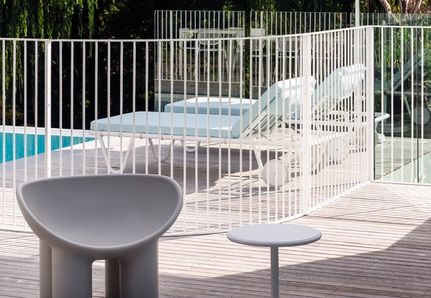 Close up of white steel pool fence and sun loungers under umbrella