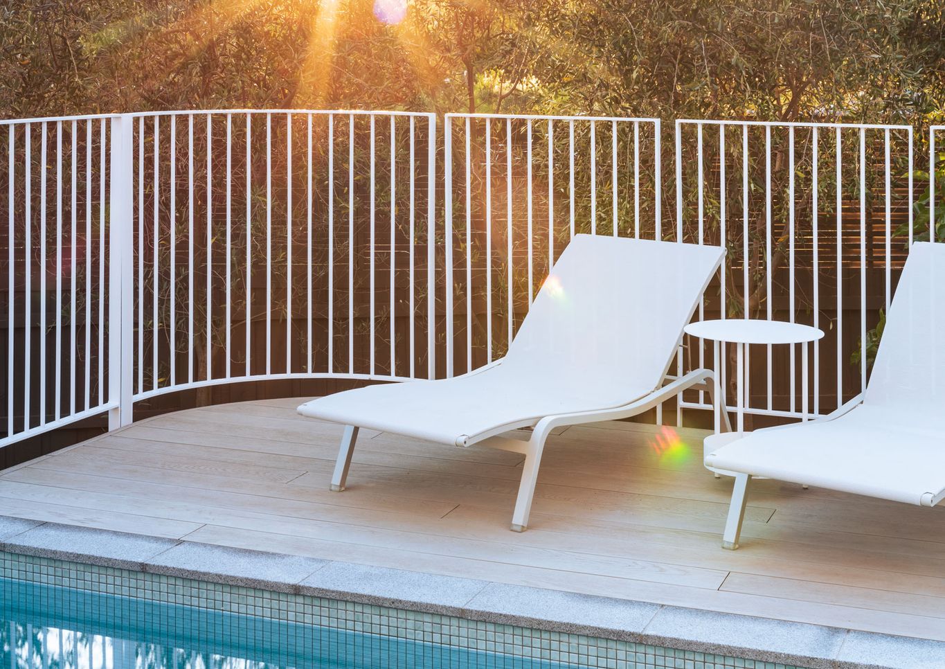 Curved pool fence and sun loungers on deck