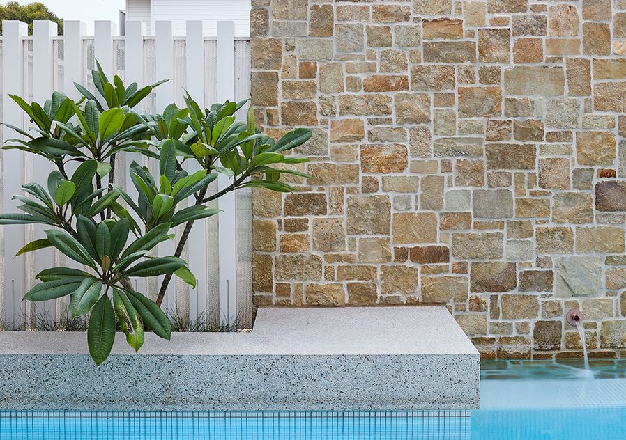 Pool tile feature photo with stone wall and green-blue spa tiles.