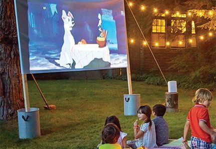 Kids watching lady and the tramp movie on a screen in the garden