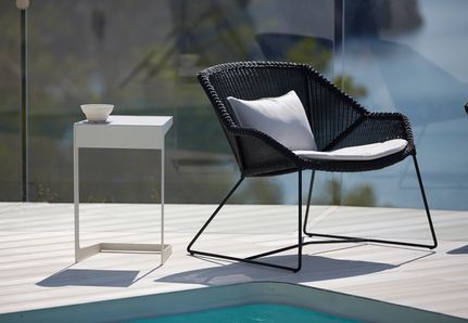 Black chair and white table sitting poolside