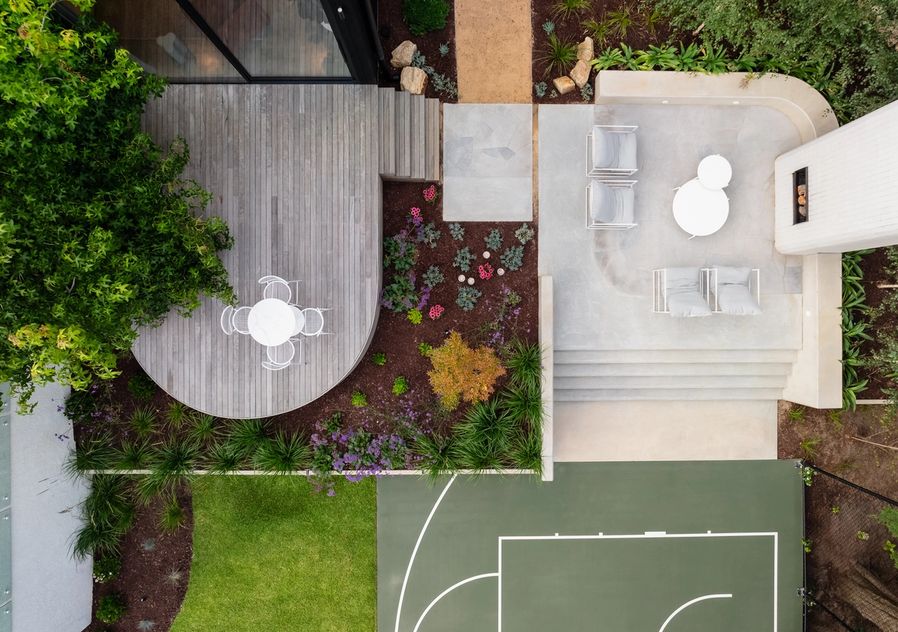 Aerial view of backyard featuring the outdoor fireplace, basketball court and curved decking area