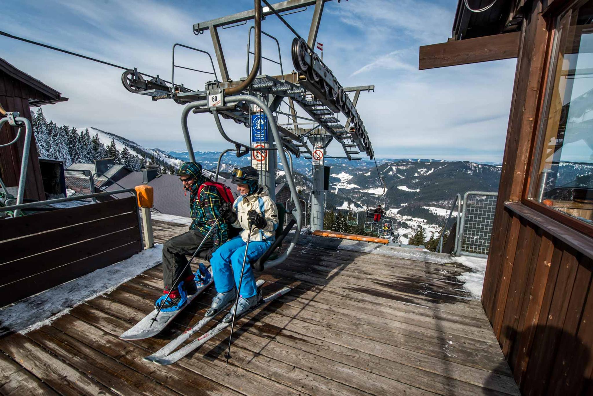 Ein Snowboarder und eine Skifahrerin beim Ausstieg vom Zweier-Lift