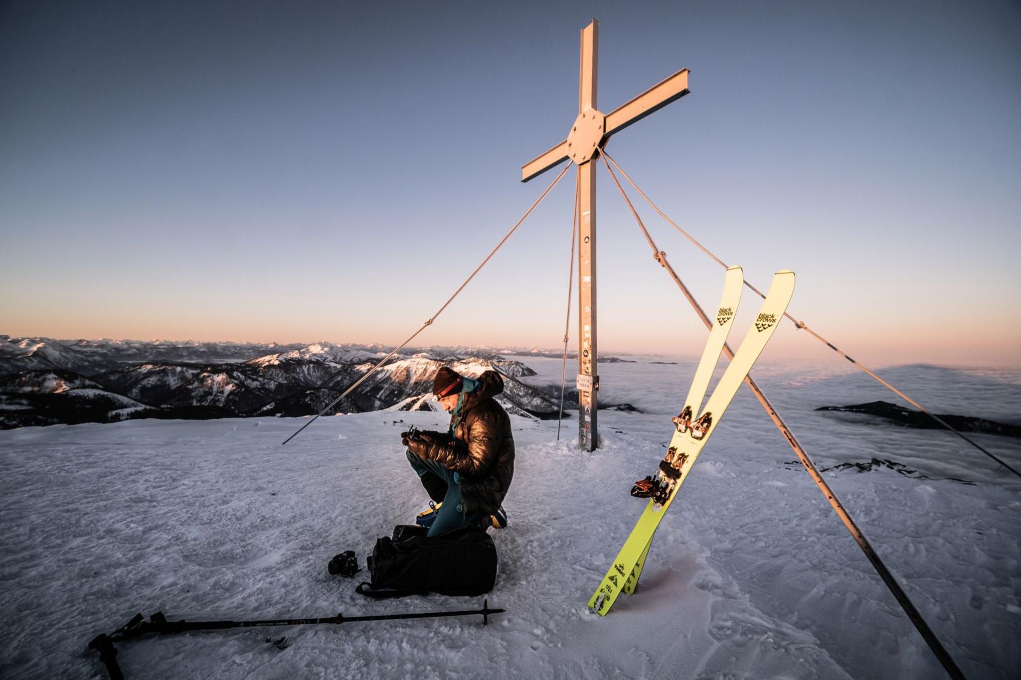 Skifahrer macht Pause beim Gipfelkreuz