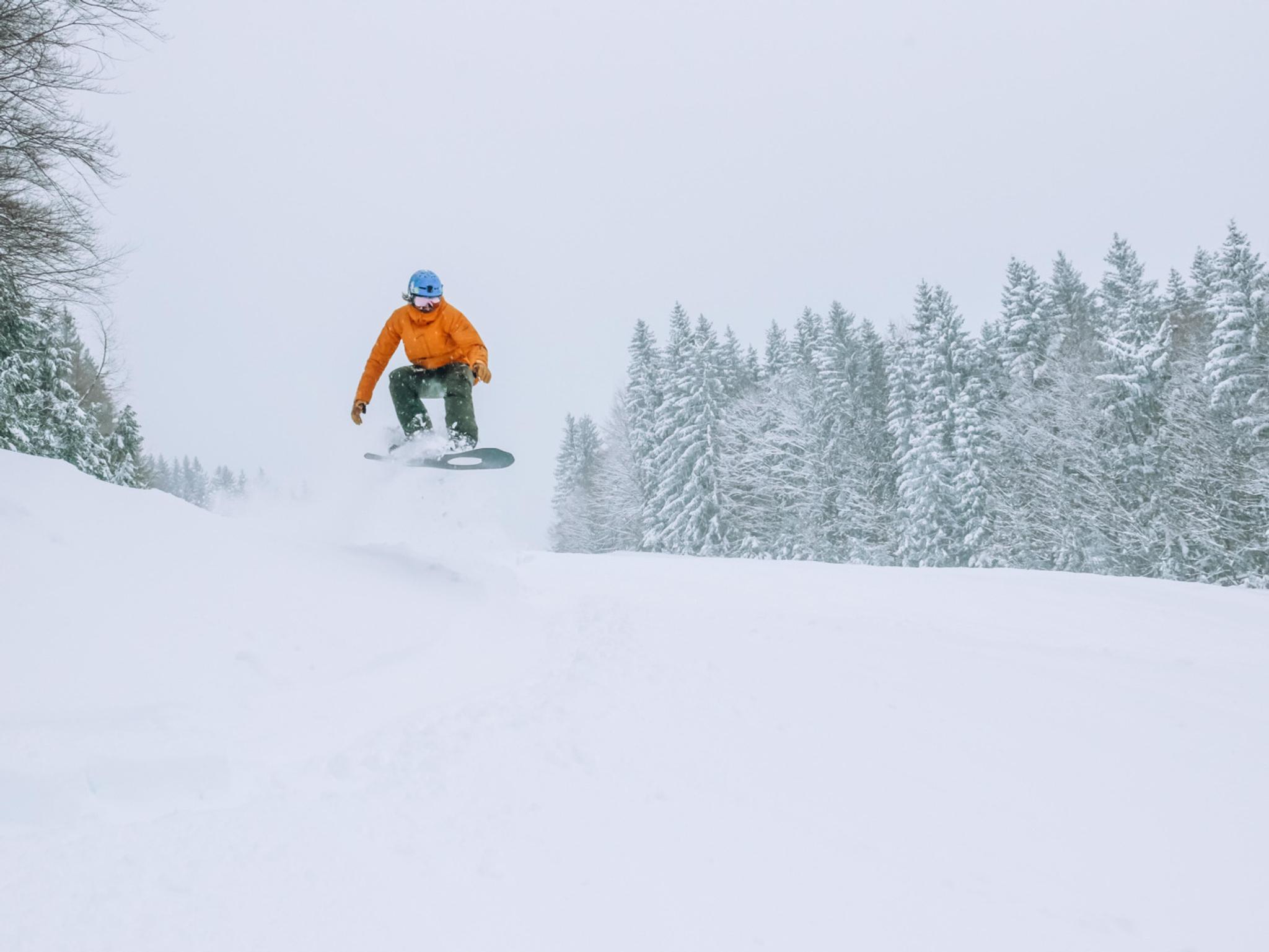 Ein SNowboarder springt auf die Piste