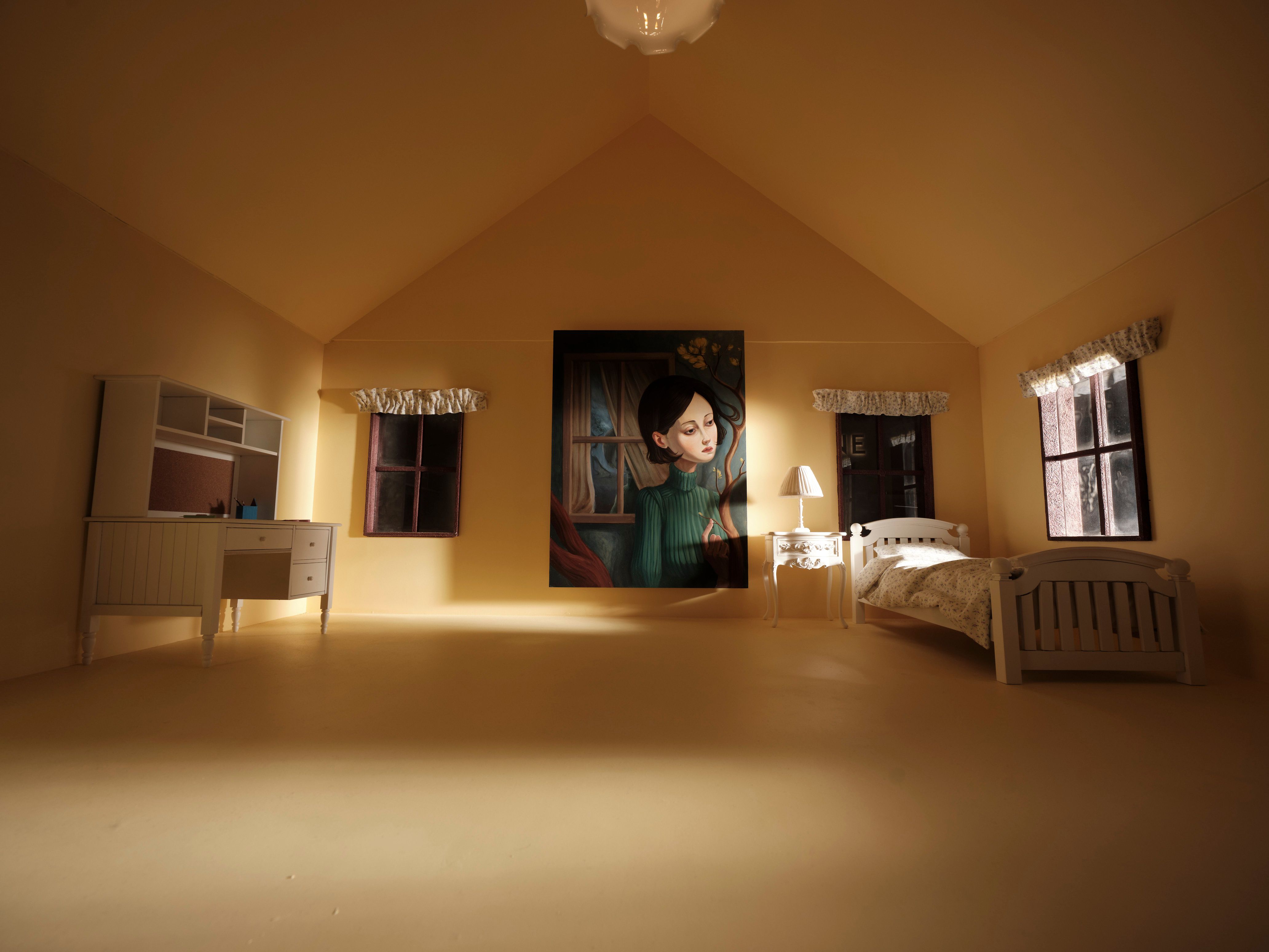 Miniature bedroom with a white bed, desk, lit lamp, three windows, and a large portrait of a woman