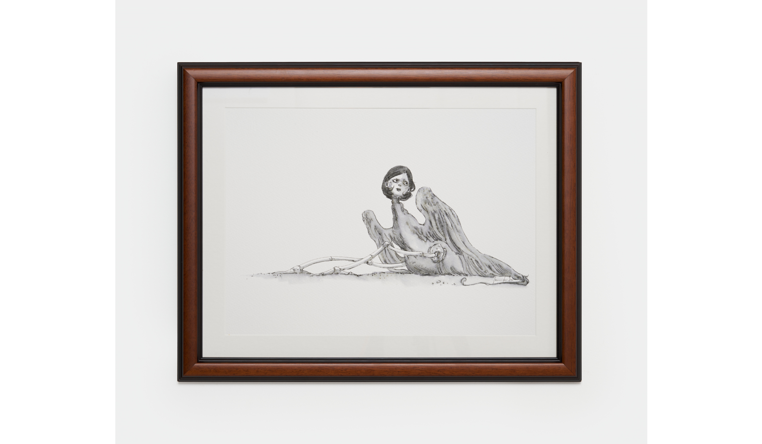Framed monochrome drawing of a winged, human-faced creature reclining beside skeletal limbs.