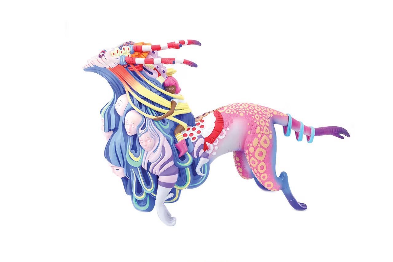 Colorful surreal sculpture of a spotted, long-tailed creature adorned with layered faces and striped horns