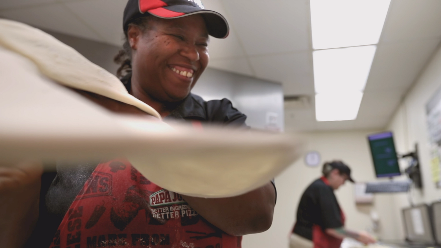 A smiling Papa John's employee, hand-tossing a pizza crust. A smiling Papa John's employee, hand-tossing a pizza crust.