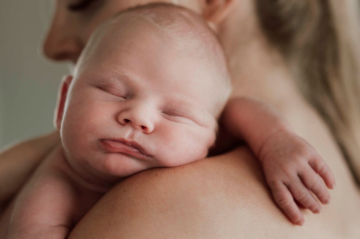 Nyfødt baby på armen til mamma