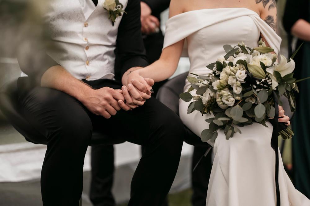 Brudepar holder hender under vielsen