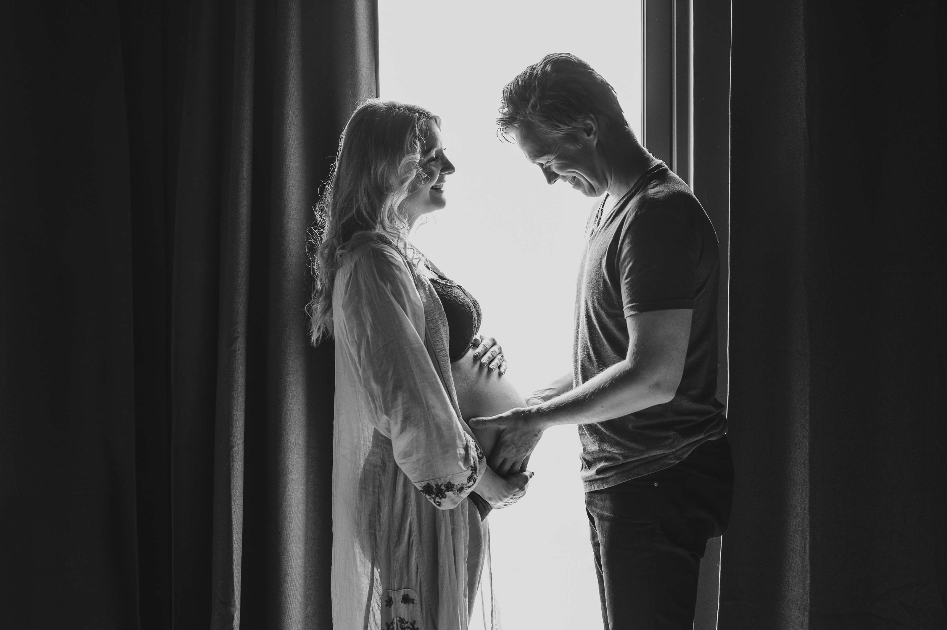 Kjærestepar står ved vinduet - hun er gravid og ventetiden er snart over