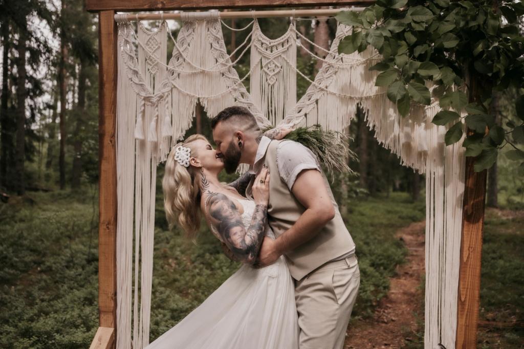 Bryllupsfotografering - Fotostorie - Brudepar kysser under en makrameportal laget av makrame_verksted