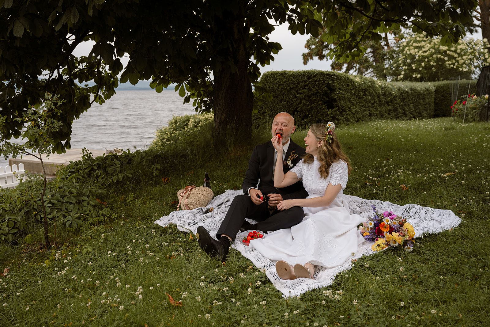 Brudepar som spiser jordbær midt i blomsterenga