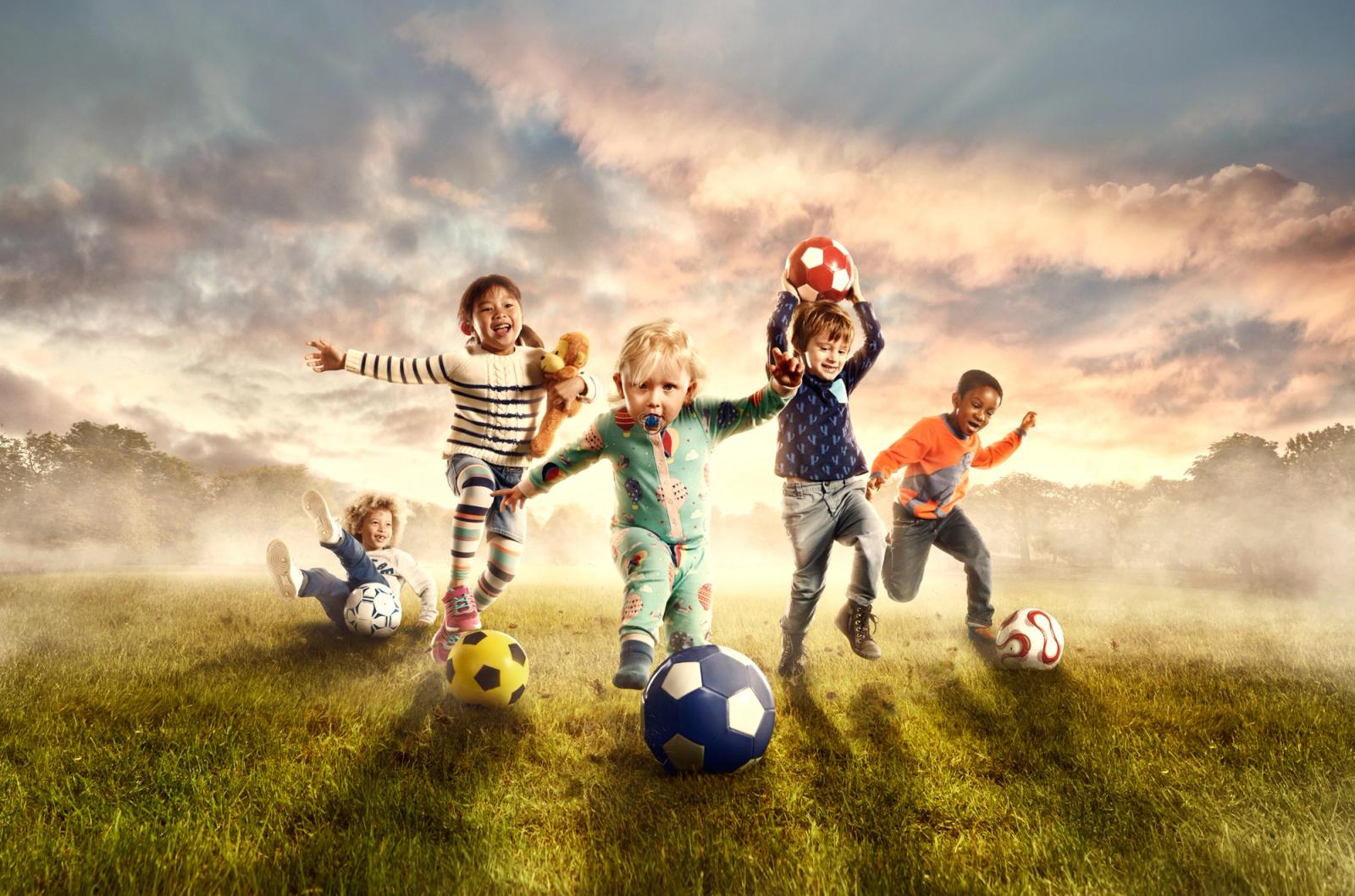 Children play with balls in a grassy field.