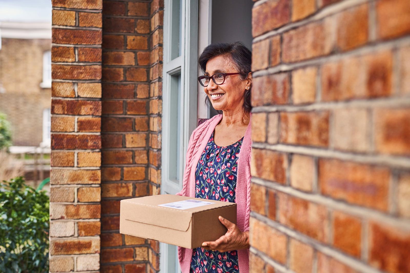 A woman holding a portfolio, standing in front of a brick wall.