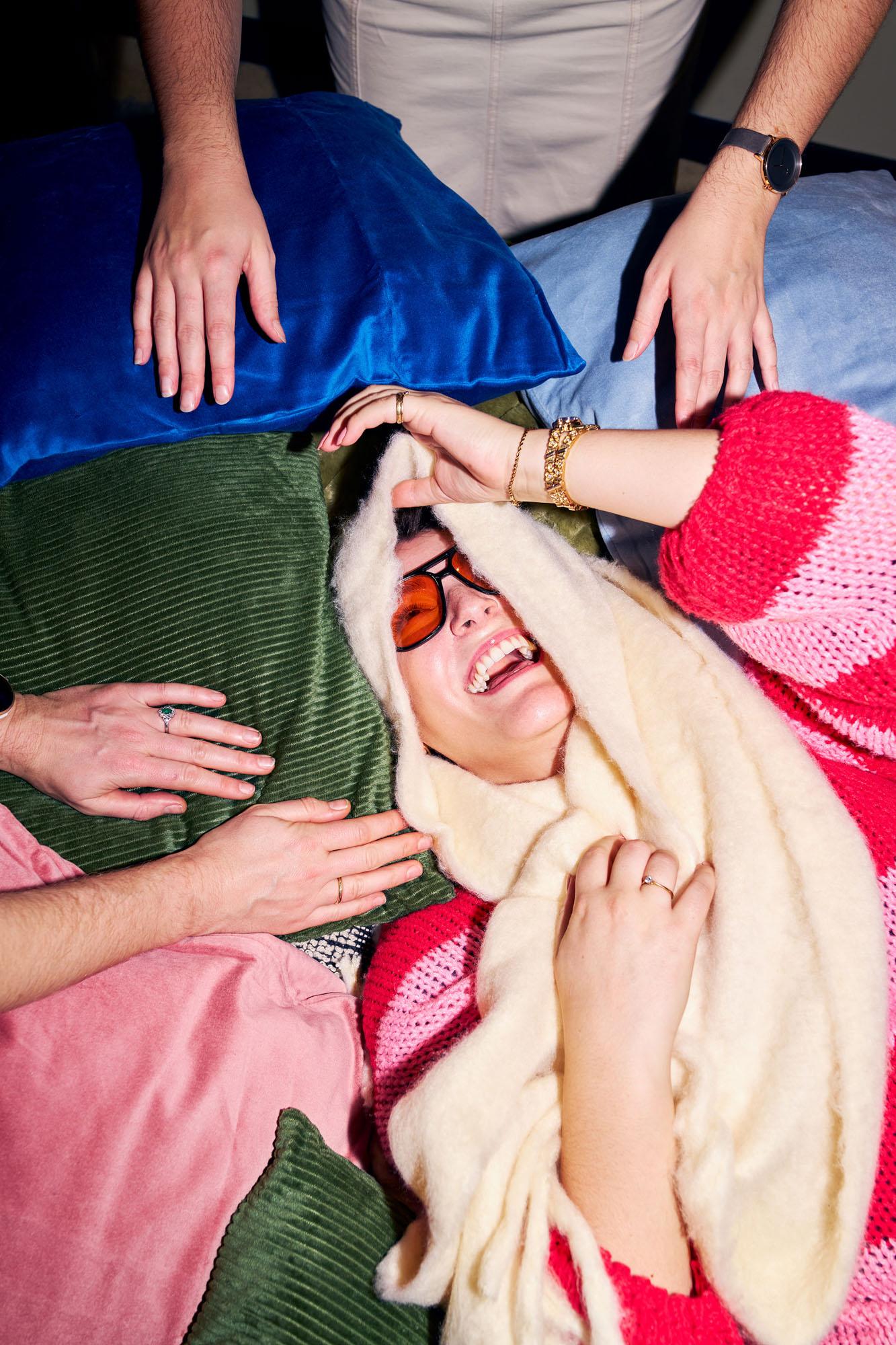 A woman surrounded by multiple people, all of whom are touching or holding onto her, in a crowded and chaotic environment.