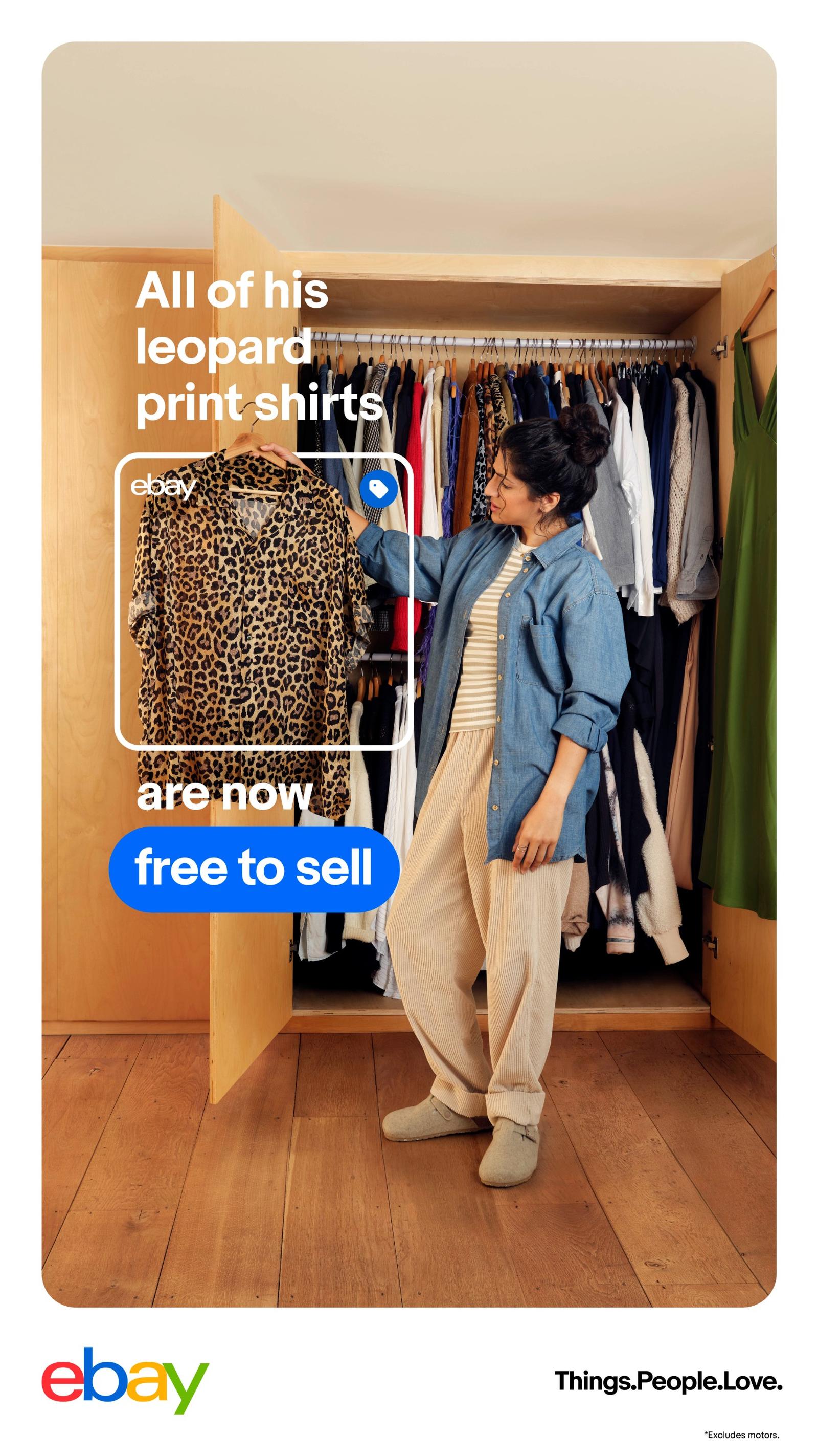 A woman in a blue denim shirt and beige pants is standing in front of a large closet, holding a leopard print shirt.