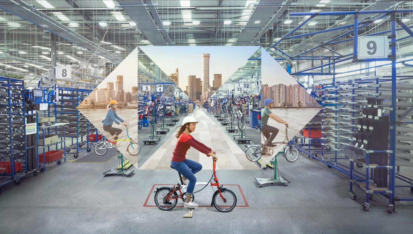 A woman in a red shirt and blue jeans riding a red bicycle in a warehouse with blue shelving and a city skyline in the background.