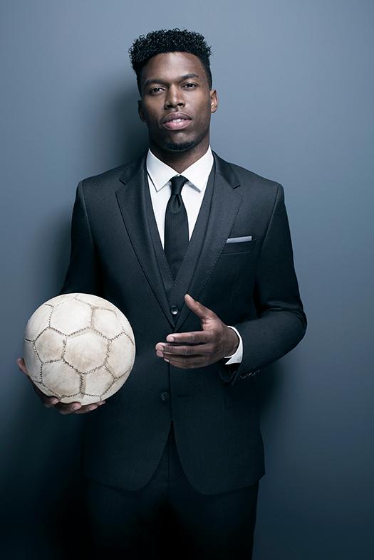A man in a black suit holding a white soccer ball.