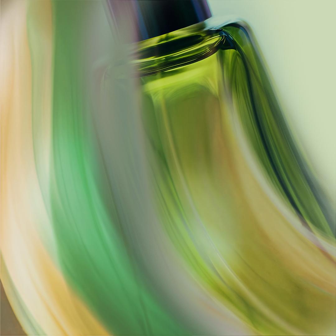 A close-up of a perfume bottle with a green glass body and a silver cap, reflecting light and creating a sense of luxury and sophistication.