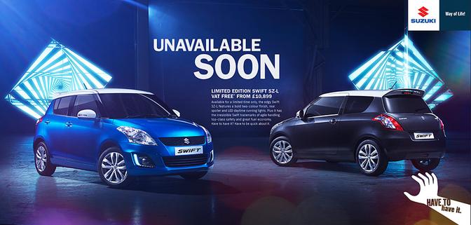 A blue Suzuki car is parked in a dark room with a neon light in the background.