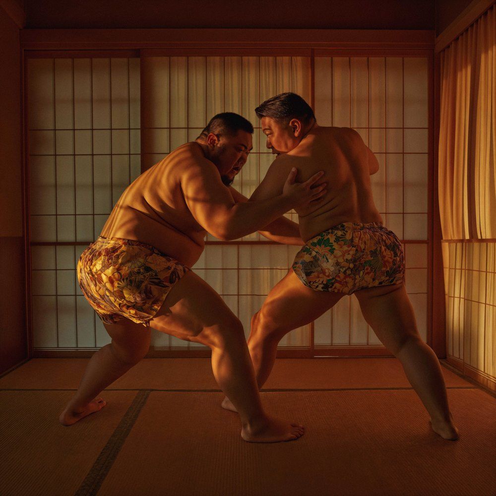 Two sumo wrestlers in traditional loincloths, or mawashi, facing off in a sumo wrestling match in a traditional Japanese sumo ring, or dohyo.